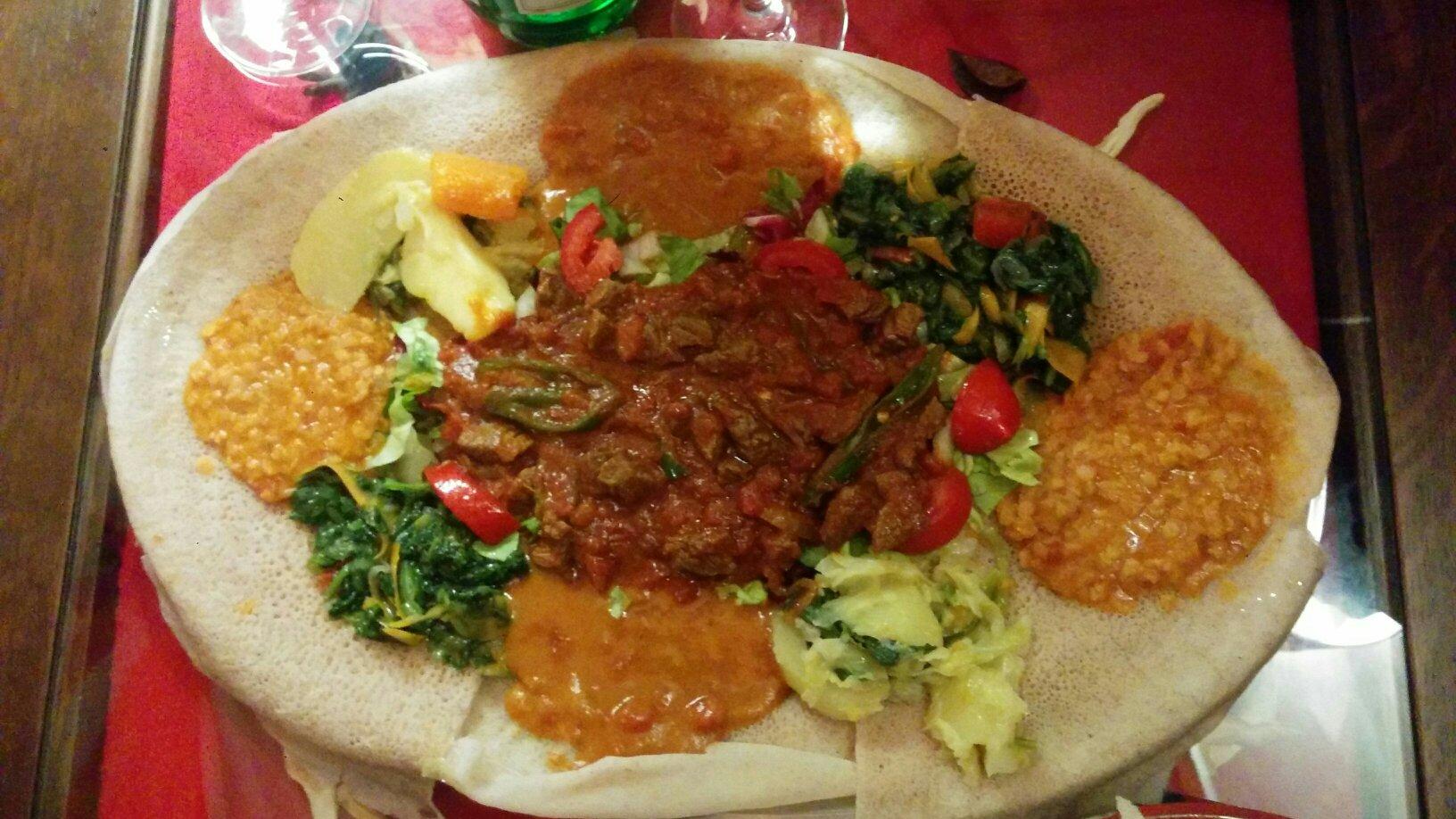 Grande piatto di injera con zighinì, verdure, lenticchie e spezie da condividere